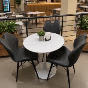Round marble dining table with three grey upholstered chairs in a modern dining setup