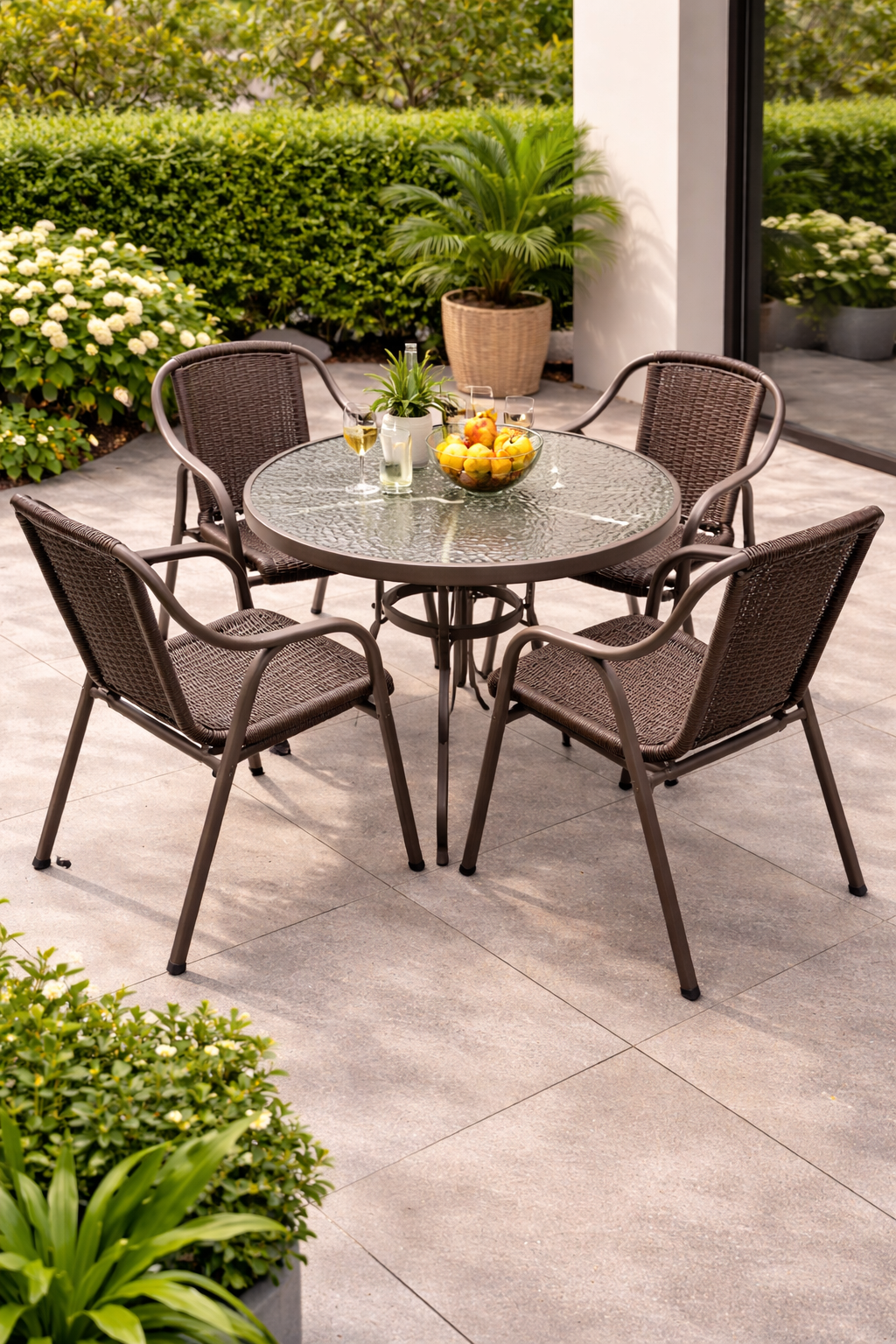 4-seater round glass top outdoor dining set with woven chairs arranged neatly in a modern patio garden setting