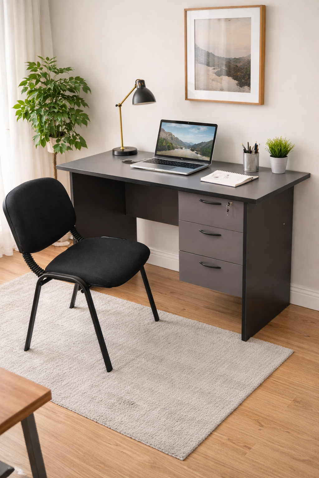 Compact office desk with drawer and comfortable visitor chair in a modern workspace