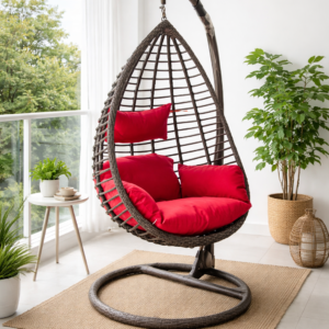 Luxury rattan hanging egg chair with red cushions on a cozy white balcony indoor setup with plants and natural light