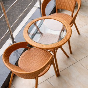 Cozy wicker patio outdoor setup with two woven chairs and a glass-top table on a balcony