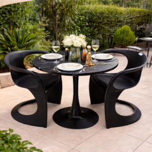 Modern black marble outdoor dining table with three sculptural black chairs on a stylish patio surrounded by greenery.