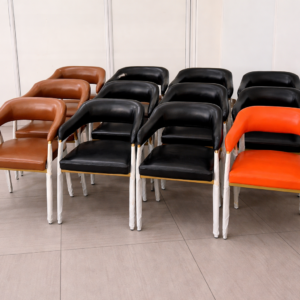 Set of modern faux leather dining chairs with curved backrest and metallic legs in black, brown, and orange colors