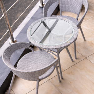Light grey wicker bistro set with two chairs and a glass-top table on a modern patio