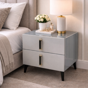Modern bedroom bedside table with glossy finish, black legs, and gold-accented handles in a stylish bedroom setup.