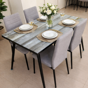 Elegant rustic dining table with glass top and four grey upholstered chairs in a modern dining setup.
