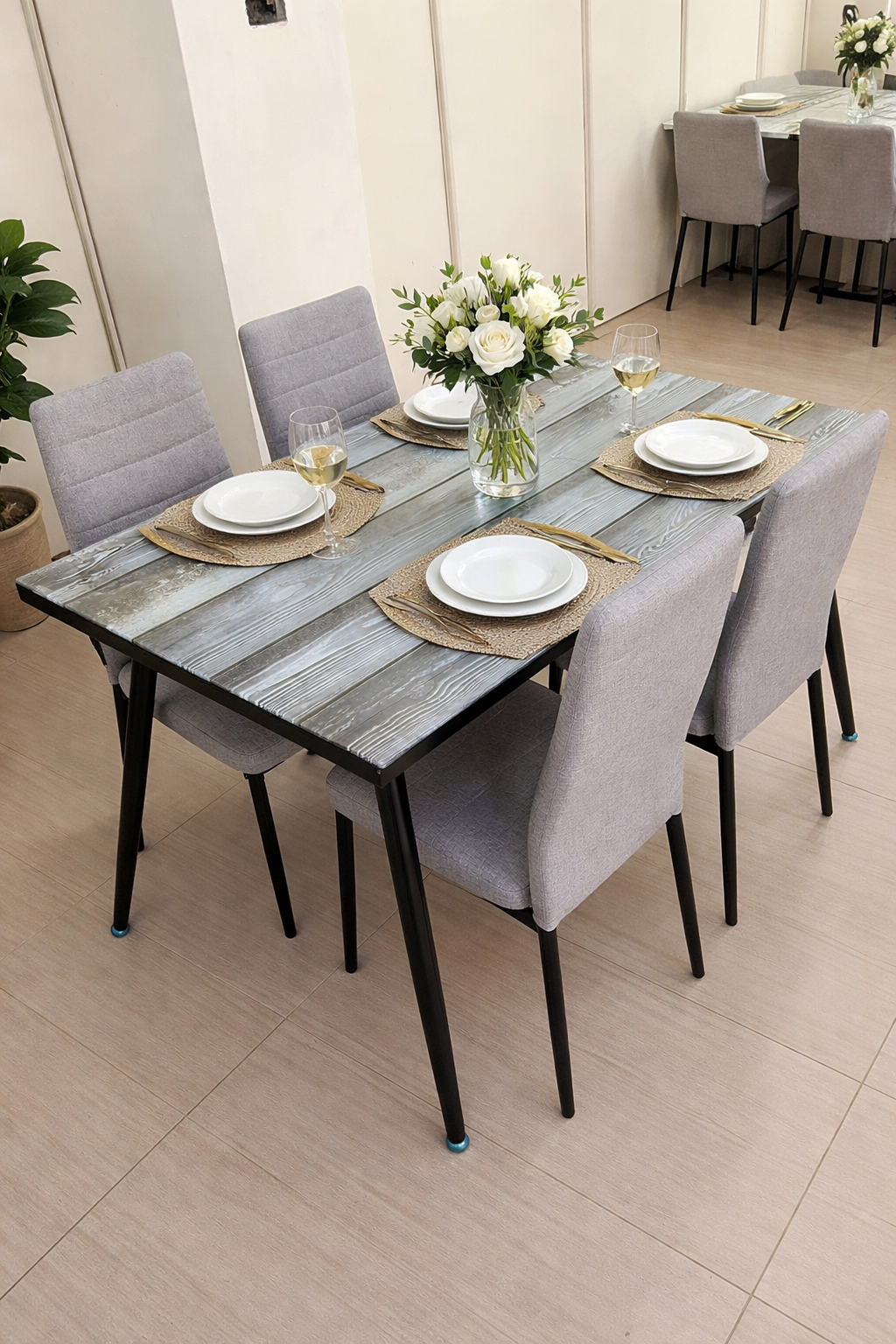 Elegant rustic dining table with glass top and four grey upholstered chairs in a modern dining setup.