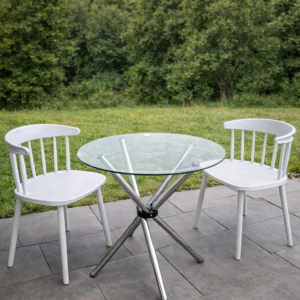 Modern patio dining set with round glass table and white chairs in an outdoor garden setup