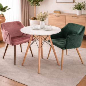 Modern dining set with a round white table and velvet chairs in green and pink, styled in a cozy dining room setup.
